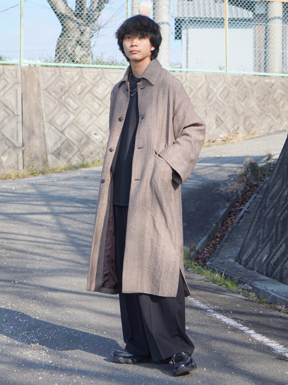 ベージュ系のステンカラーコート、ブラック系のTシャツ/カットソー、ブラック系のスラックスを着用したメンズの秋コーディネートの1枚目の写真