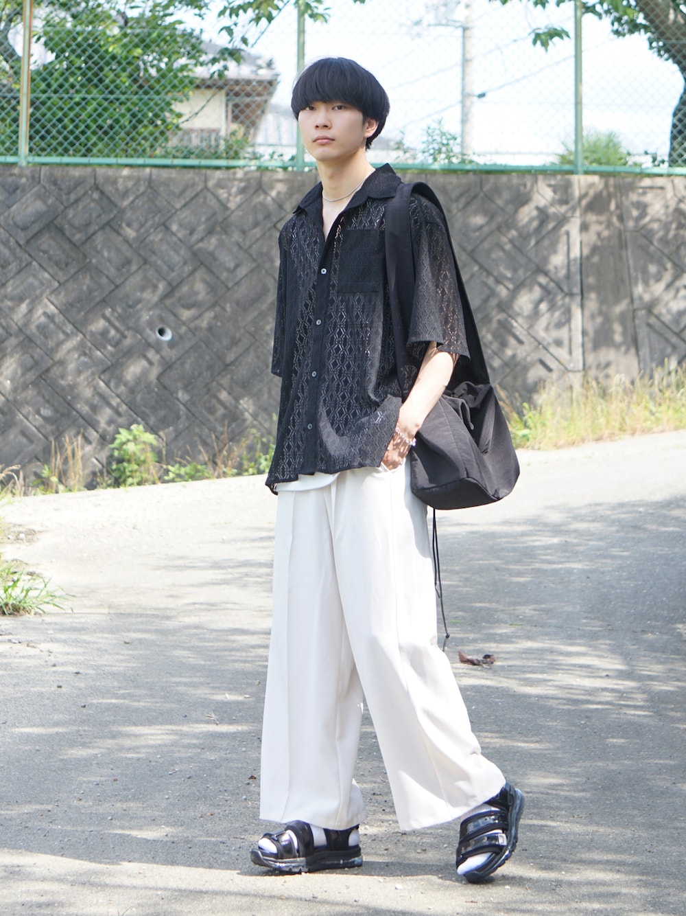 ブラック系のシャツ/ブラウス、ベージュ系のスラックス、ホワイト系のサンダルを着用したメンズの夏コーディネートの1枚目の写真
