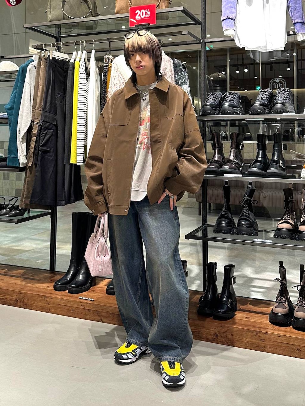 ブルー系のデニムパンツ、ピンク系のハンドバッグ、ベージュ系のスウェットを着用したメンズの冬コーディネートの1枚目の写真