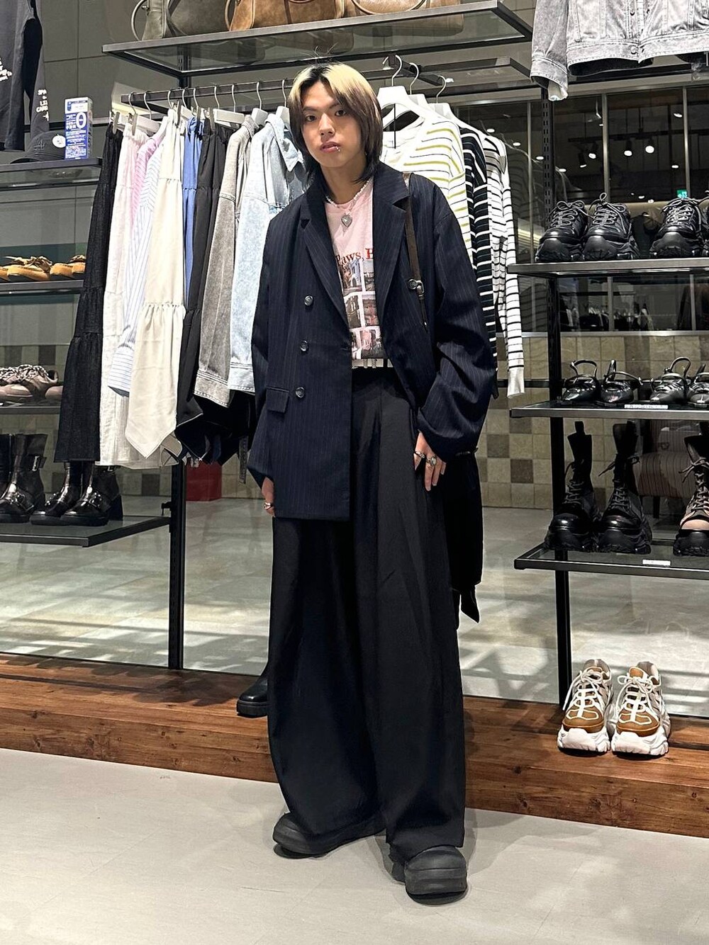 ブラック系のスラックス、ブラウン系のショルダーバッグ、ピンク系のTシャツ/カットソーを着用したメンズの春コーディネートの1枚目の写真