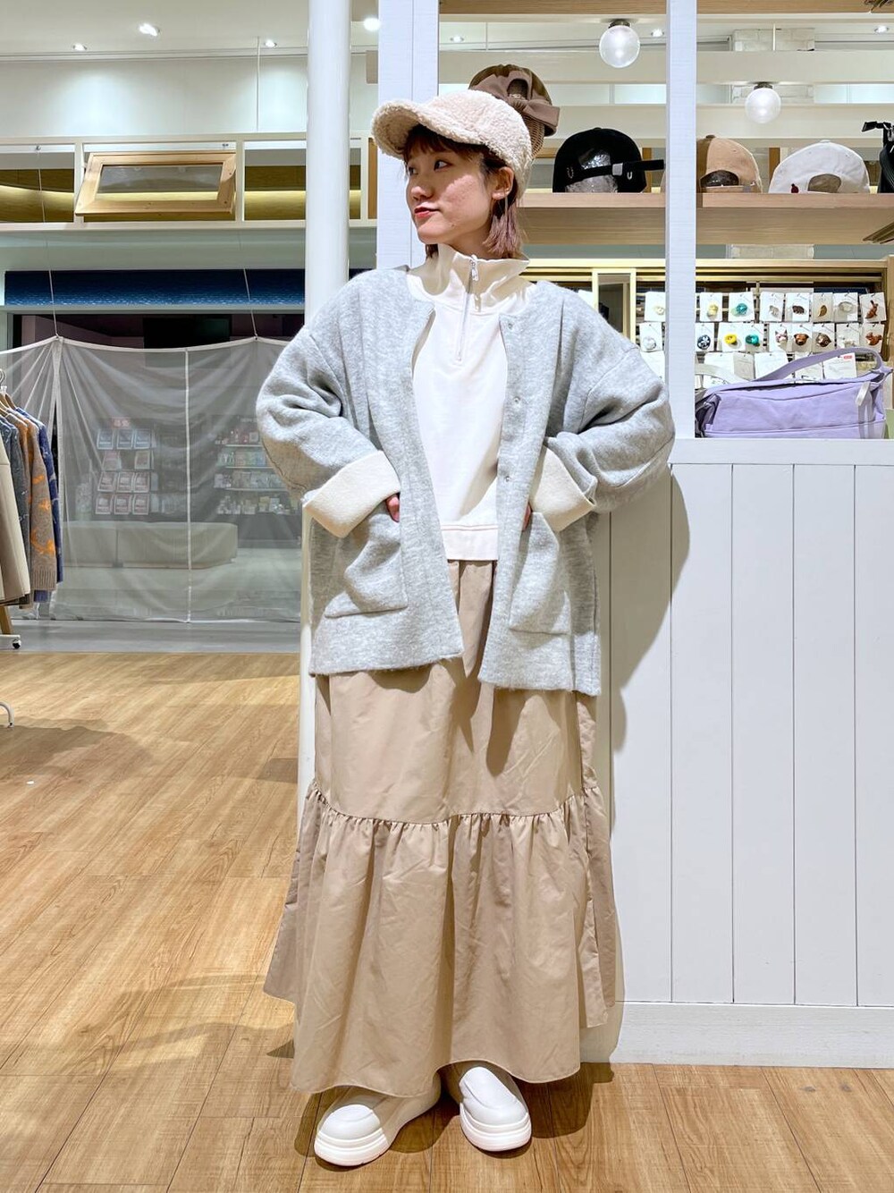 ホワイト系のスリッポン、グレー系のノーカラーコート、ベージュ系のワンピースを着用したレディースの冬コーディネートの1枚目の写真