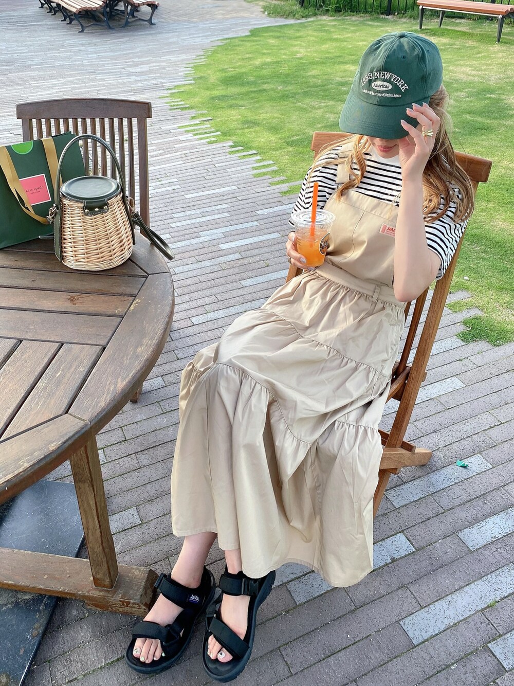 ベージュ系のワンピース、ブラック系のサンダル、ホワイト系のTシャツ/カットソーを着用したレディースの春コーディネートの1枚目の写真