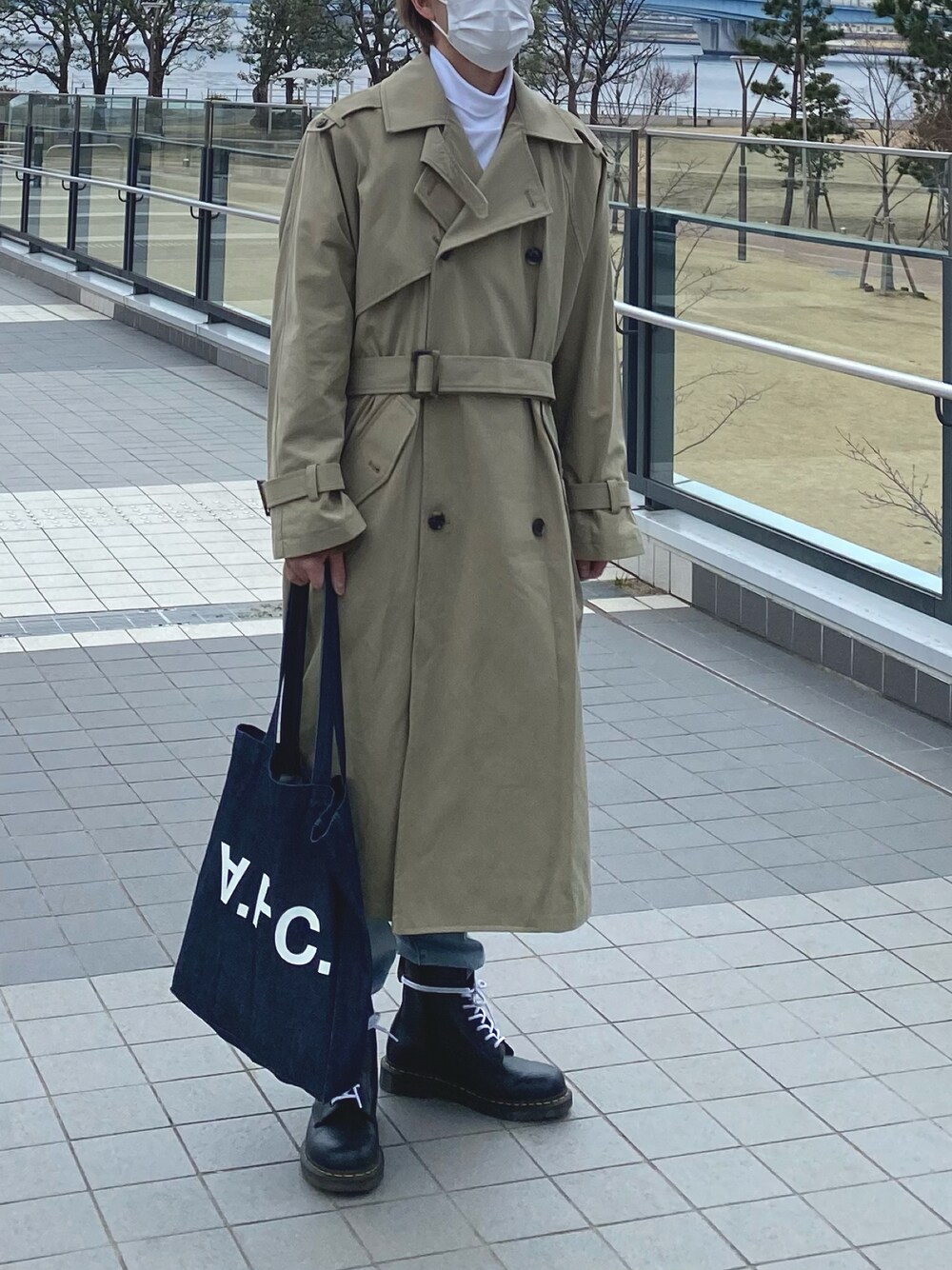 「春コーデ、シンプルコーデ、ミリタリー、カジュアル、トレンチコート、ロングコート、デニム、ブーツ、リーバイス、A.P.C.、Dr.Martens、soerte」｜「A.P.C.の【A.P.C】インディゴトートバッグ COCSX IAI INDIGO（トートバッグ、ブルー系）」を使った、プーシャンさん（メンズ・171cm）の春コーディネートの1枚目の写真