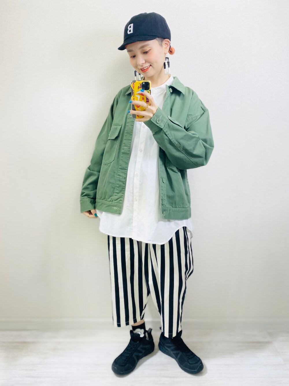 グリーン系のデニムジャケット、ホワイト系のシャツ/ブラウス、ブラック系のキャップを着用したレディースの春コーディネートの1枚目の写真