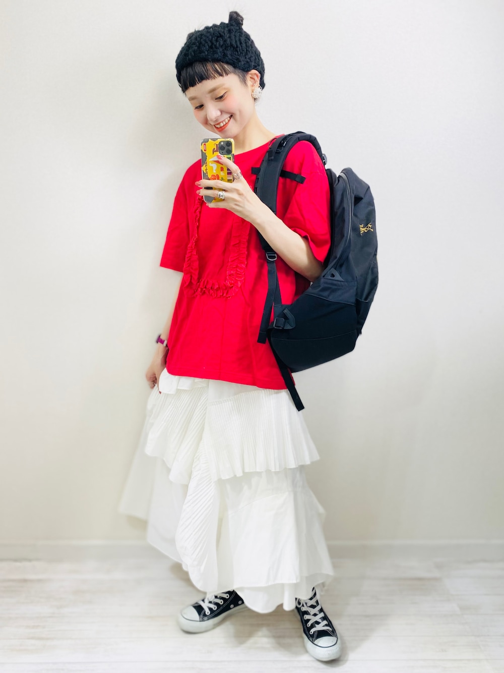 ブラック系のバックパック/リュック、レッド系のTシャツ/カットソー、ホワイト系のスカートを着用したレディースの春コーディネートの1枚目の写真