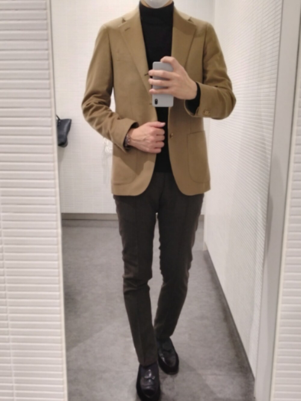 ブラック系のスリッポン、ブラウン系のスラックス、ベージュ系のテーラードジャケットを着用したメンズの春コーディネートの1枚目の写真