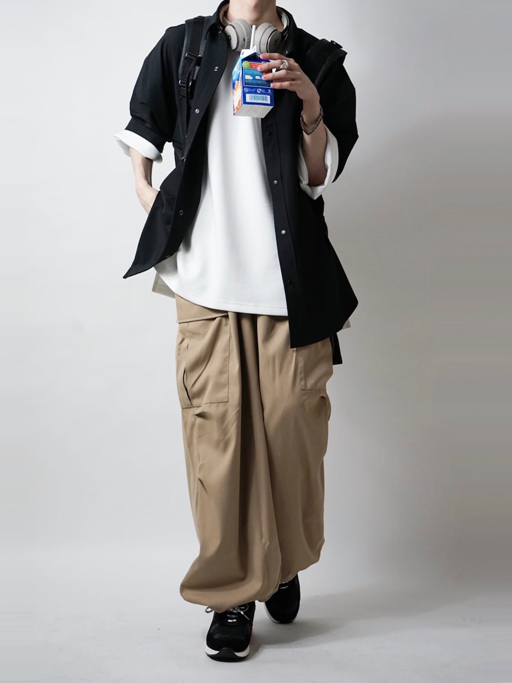 ベージュ系のカーゴパンツ、ホワイト系のTシャツ/カットソー、ブラック系のスニーカーを着用したメンズの夏コーディネートの1枚目の写真