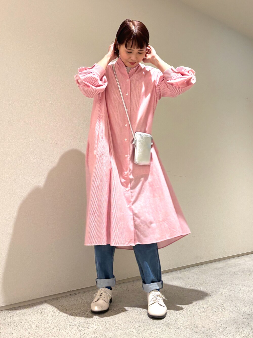 レッド系のワンピース、シルバー系のバッグ、ブルー系のデニムパンツを着用したレディースの春コーディネートの1枚目の写真