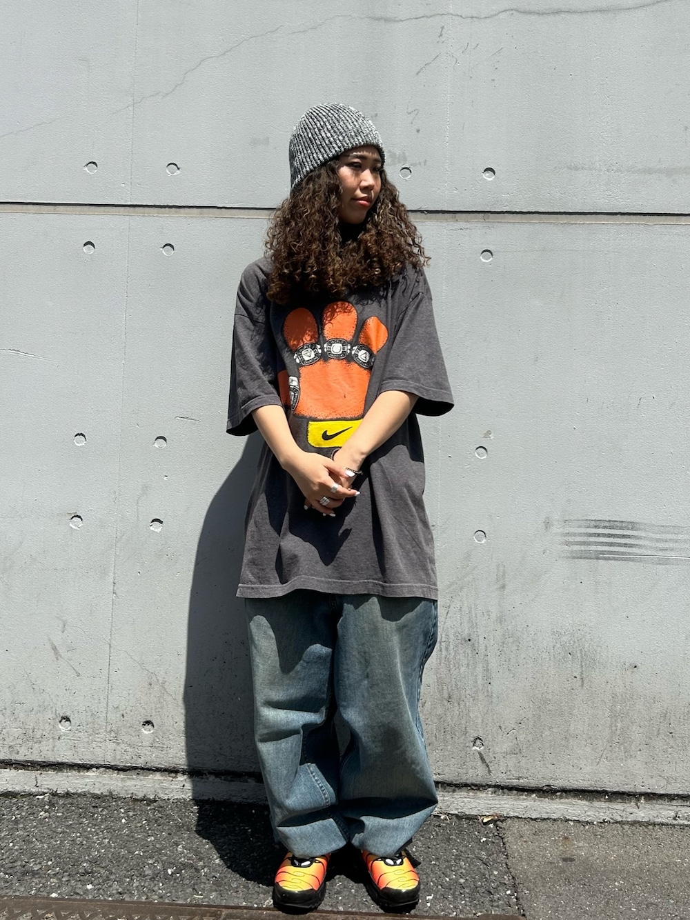 グレー系のTシャツ/カットソー、ブルー系のデニムパンツ、オレンジ系のスニーカーを着用したレディースの春コーディネートの1枚目の写真