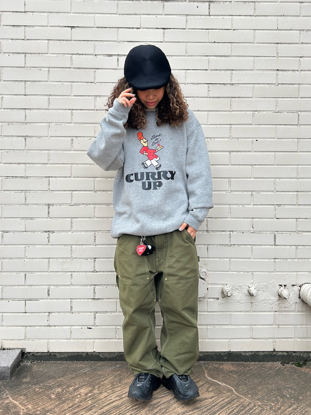 グレー系のスウェット、グリーン系のパンツ、ブラック系のスニーカーを着用したレディースの春コーディネートの1枚目の写真