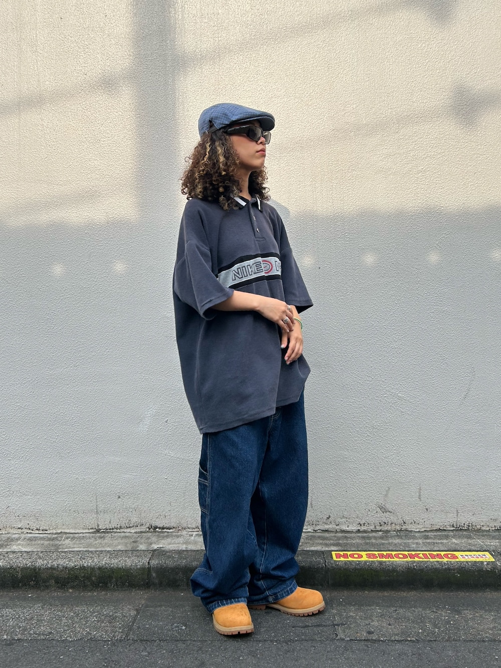 グレー系のトップス、ブルー系のデニムパンツ、イエロー系のブーツを着用したレディースの夏コーディネートの1枚目の写真