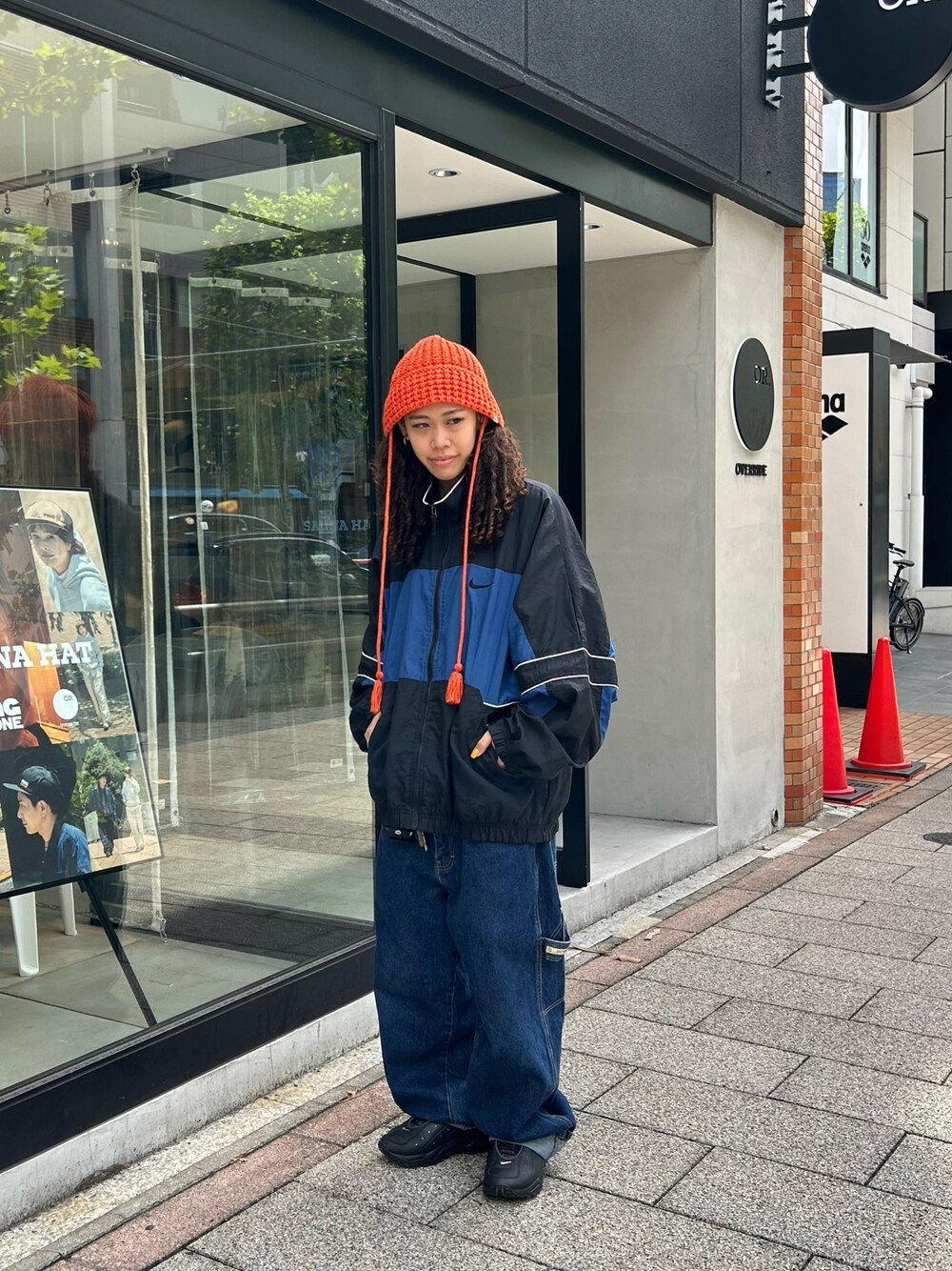 ブルー系のナイロンジャケット、ブルー系のデニムパンツ、ブラック系のスニーカーを着用したレディースの秋コーディネートの1枚目の写真