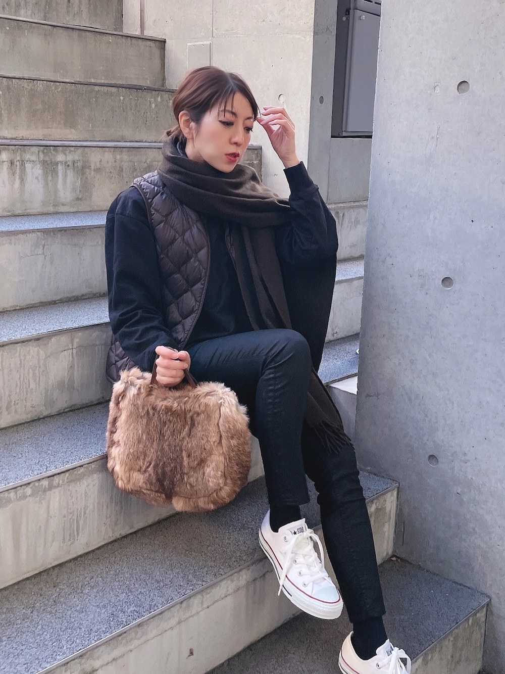 ブラック系のTシャツ/カットソー、ホワイト系のスニーカー、ブラウン系のハンドバッグを着用したレディースの冬コーディネートの1枚目の写真