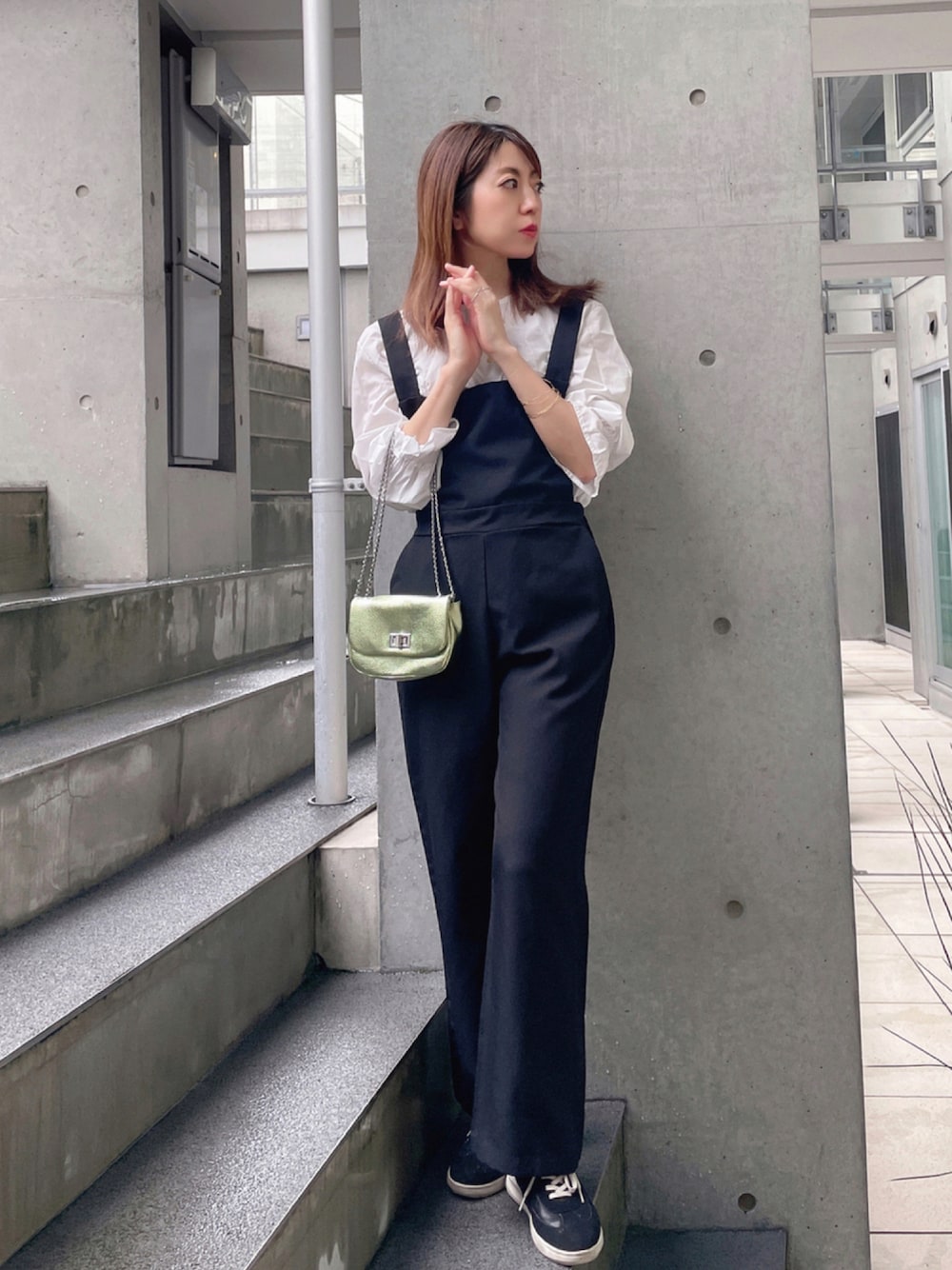 ブラック系のサロペット/オーバーオール、グリーン系のショルダーバッグ、ブラック系のスニーカーを着用したレディースの秋コーディネートの1枚目の写真