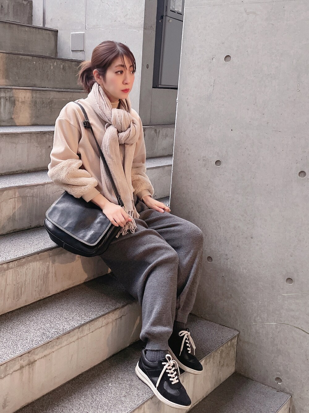 グレー系のパンツ、ベージュ系のスウェット、ブラック系のショルダーバッグを着用したレディースの冬コーディネートの1枚目の写真