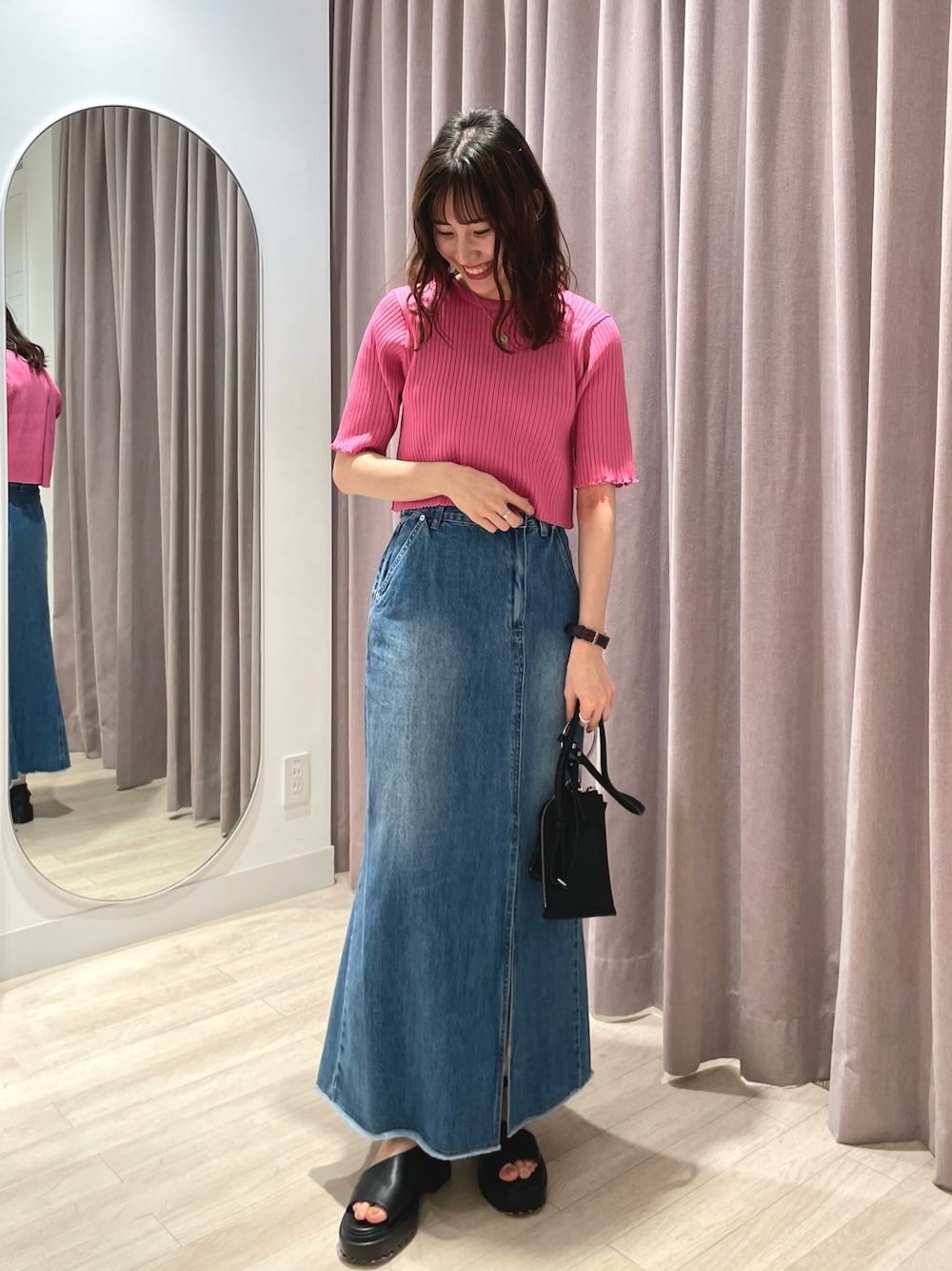 ピンク系のニット/セーター、ブルー系のデニムスカート、ブラック系のショルダーバッグを着用したレディースの春コーディネートの1枚目の写真