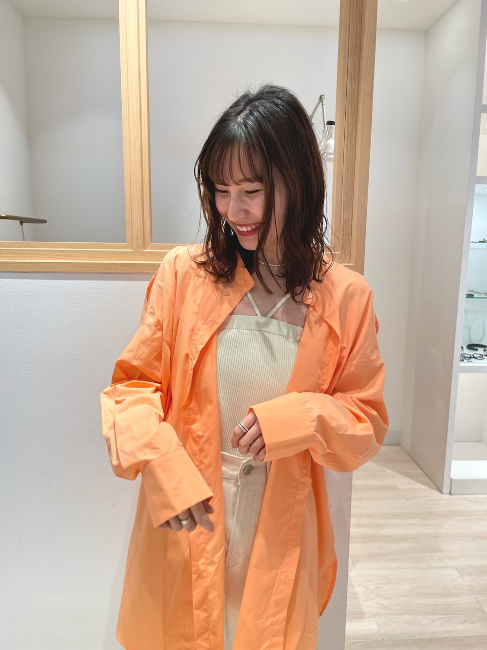 オレンジ系のシャツ/ブラウス、ホワイト系のキャミソール、ホワイト系のデニムパンツを着用したレディースの春コーディネートの1枚目の写真