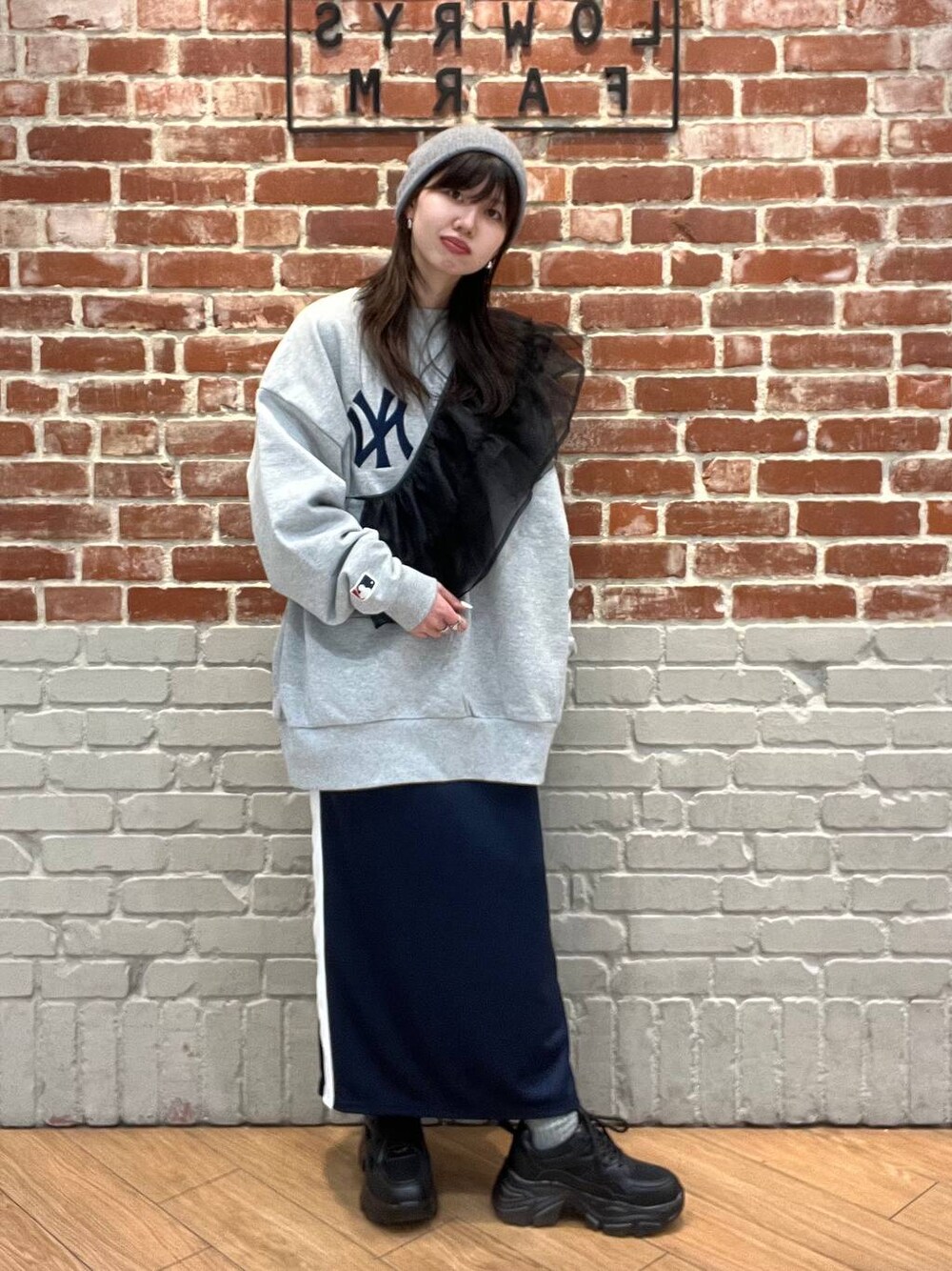 グレー系のTシャツ/カットソー、ブルー系のスカート、ブラック系のスニーカーを着用したレディースの冬コーディネートの1枚目の写真