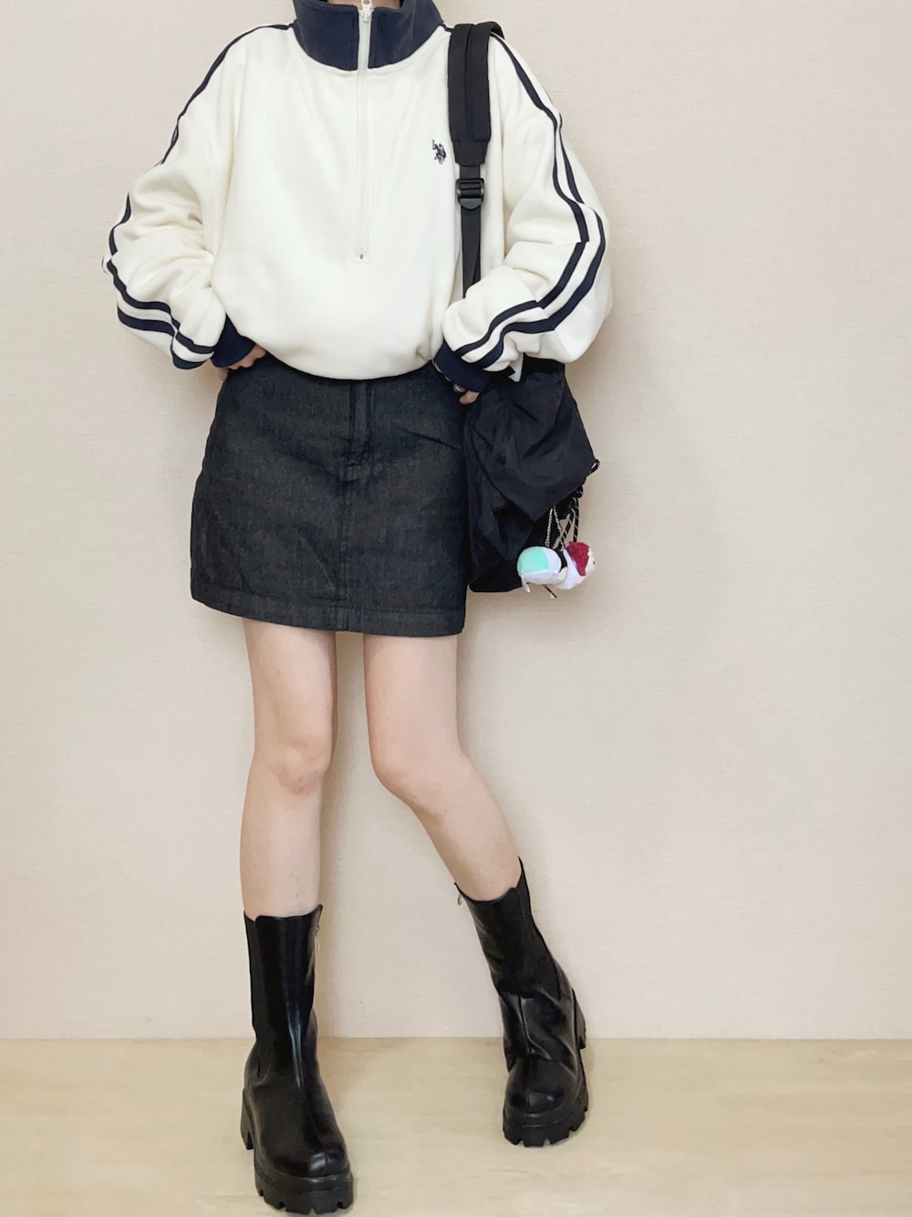 ホワイト系のスウェット、ブルー系のデニムスカート、ブラック系のブーツを着用したレディースの秋コーディネートの1枚目の写真