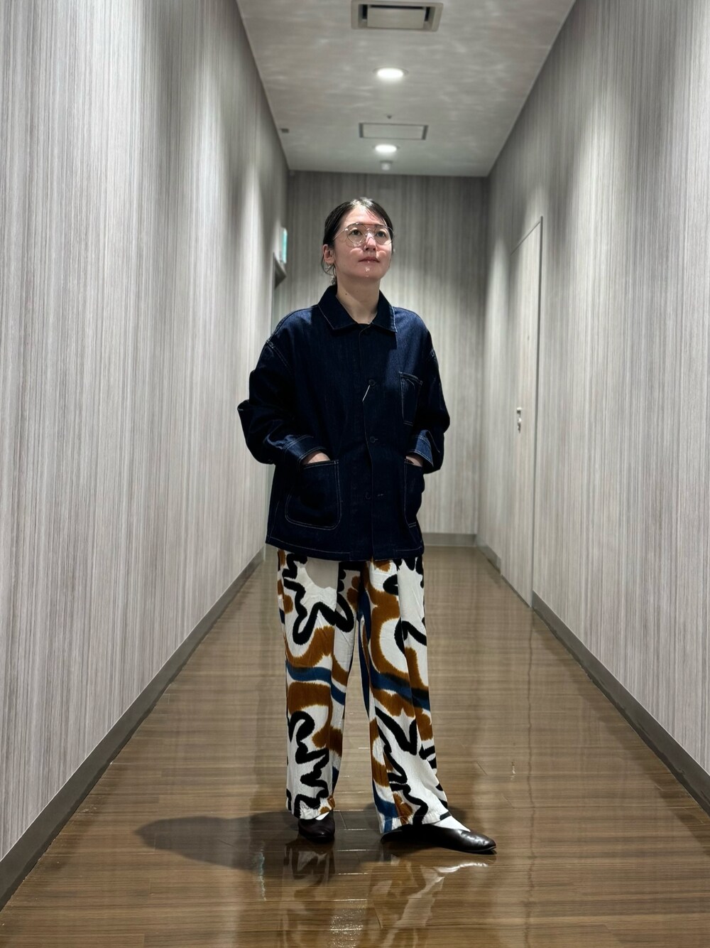 ブルー系のデニムジャケット、ブラウン系のパンプスを着用したレディースの秋コーディネートの1枚目の写真