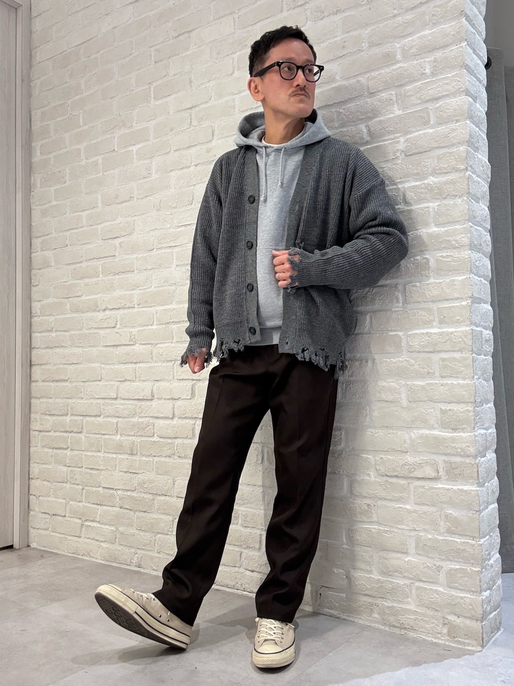 グレー系のカーディガン/ボレロ、グレー系のパーカー、ブラウン系のスラックスを着用したメンズの秋コーディネートの1枚目の写真
