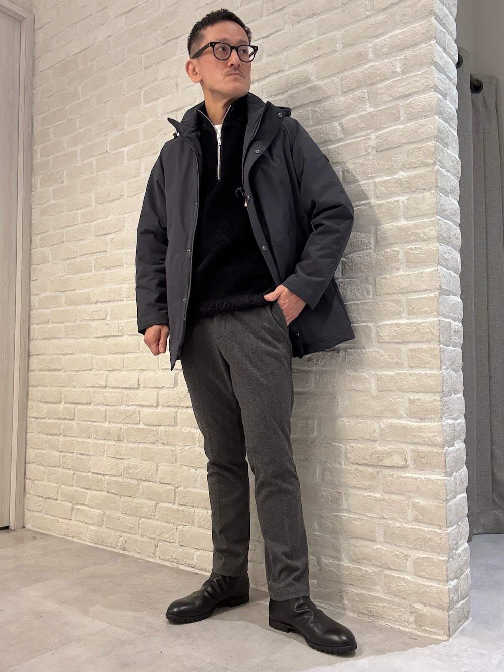 ブルー系のブルゾン、ブラック系のニット/セーター、ブラック系のスラックスを着用したメンズの冬コーディネートの1枚目の写真