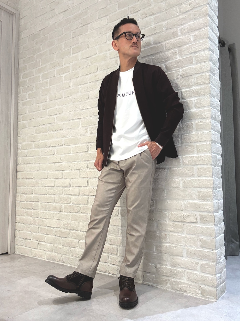 レッド系のブルゾン、ホワイト系のTシャツ/カットソー、ベージュ系のスラックスを着用したメンズの秋コーディネートの1枚目の写真