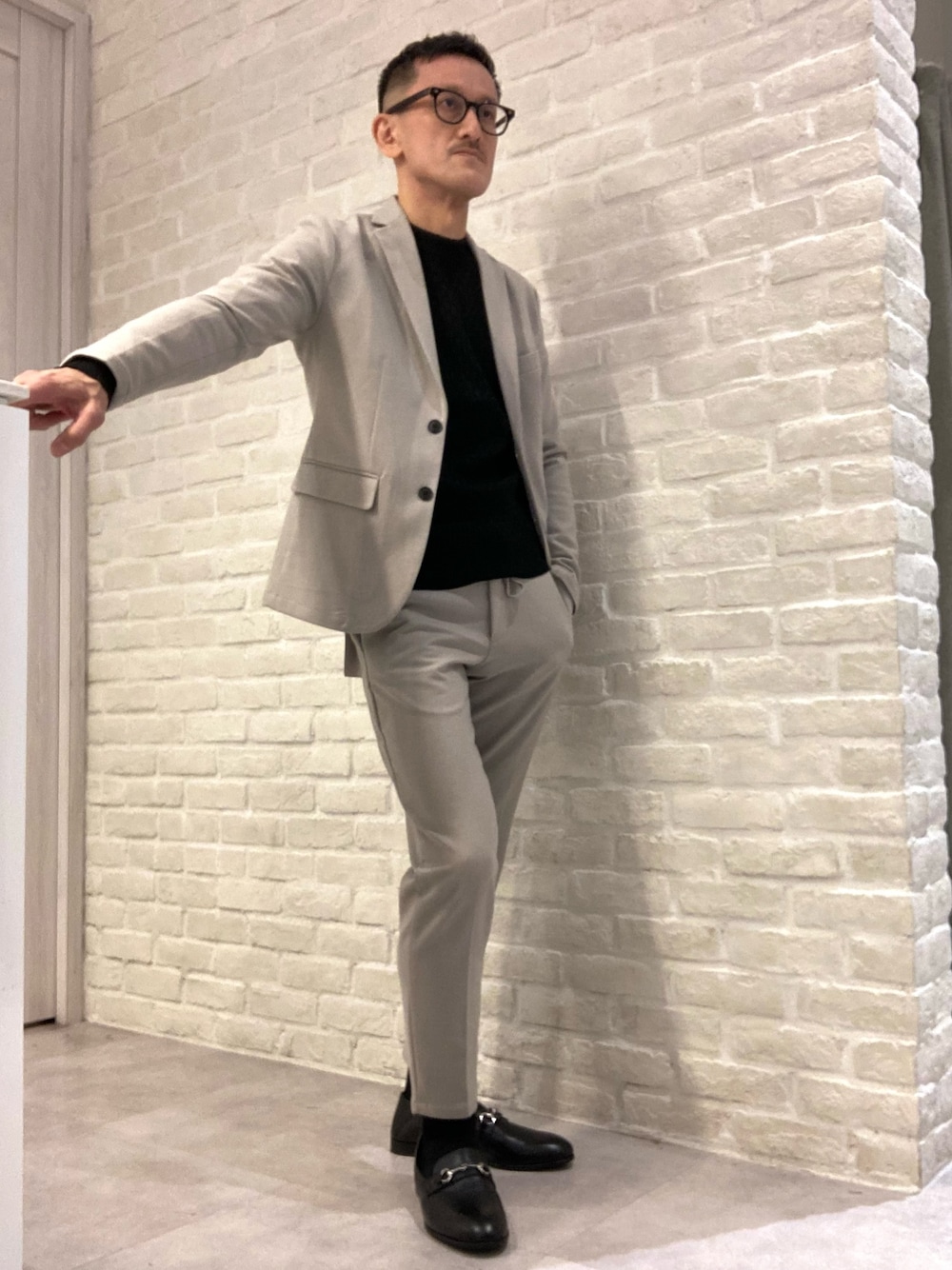 ベージュ系のセットアップ、ベージュ系のテーラードジャケット、ブラック系のニット/セーターを着用したメンズの冬コーディネートの1枚目の写真