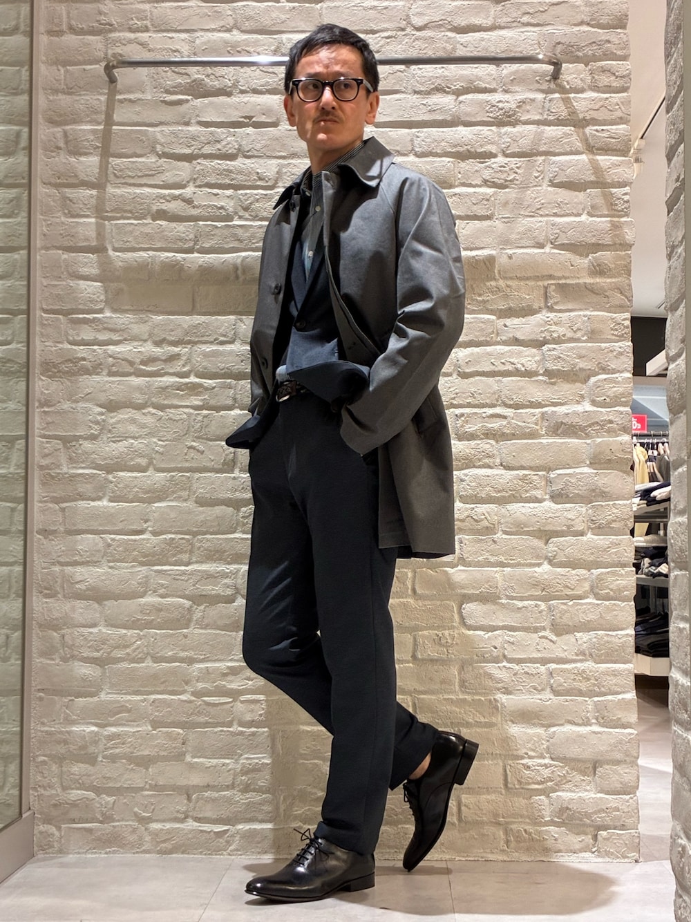 グレー系のステンカラーコート、ブルー系のテーラードジャケット、ブルー系のシャツ/ブラウスを着用したメンズの冬コーディネートの1枚目の写真