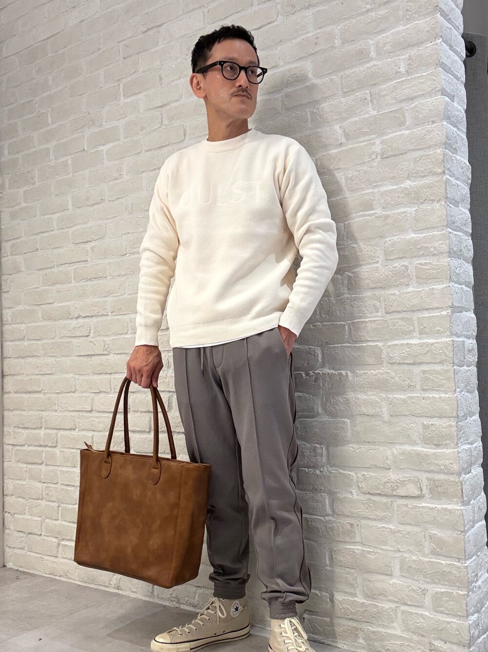 ホワイト系のニット/セーター、ブラウン系のトートバッグ、グリーン系のその他パンツを着用したメンズの秋コーディネートの1枚目の写真