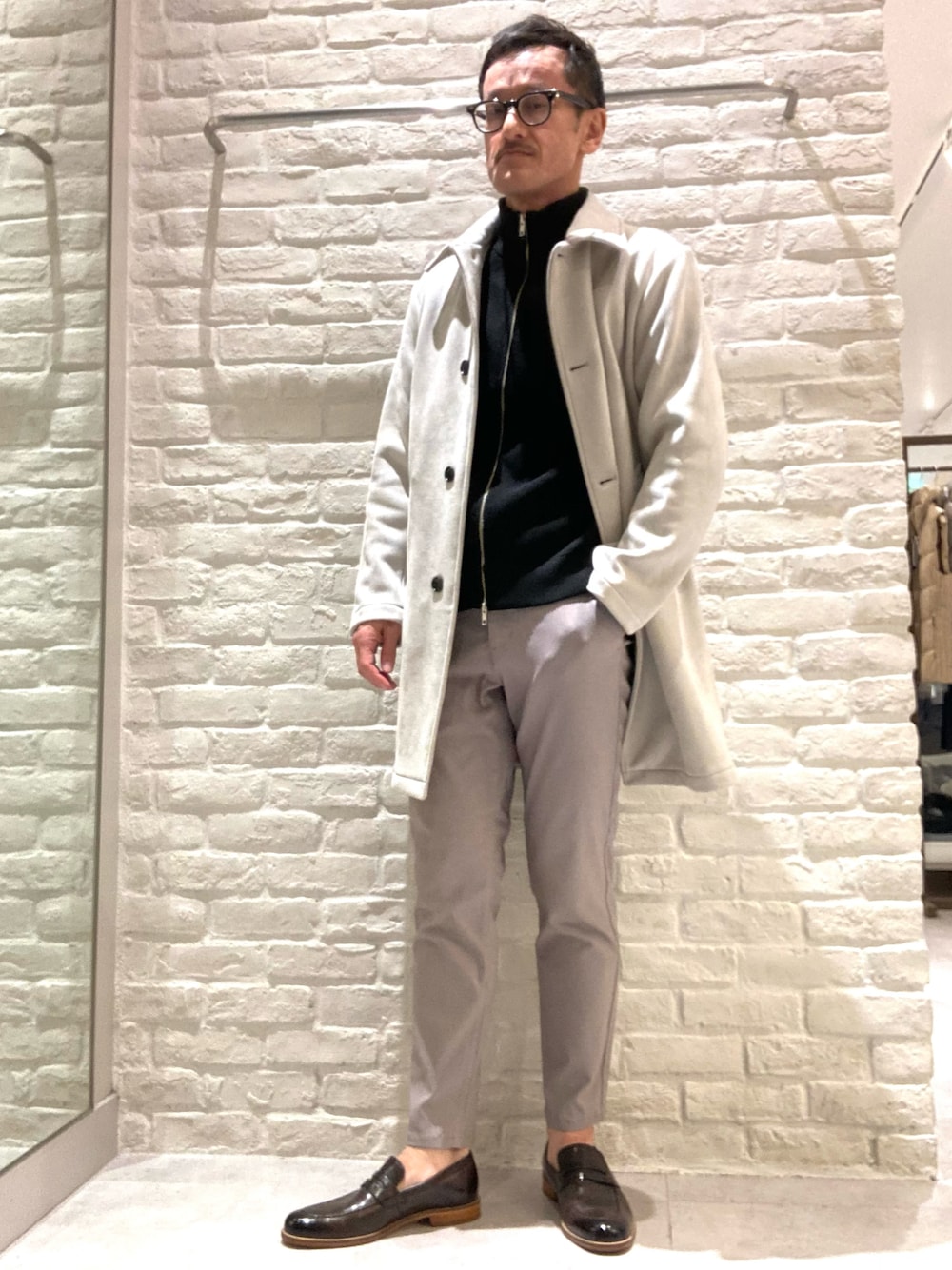 ベージュ系のステンカラーコート、ブラック系のニット/セーター、ブラック系のカーディガン/ボレロを着用したメンズの冬コーディネートの1枚目の写真