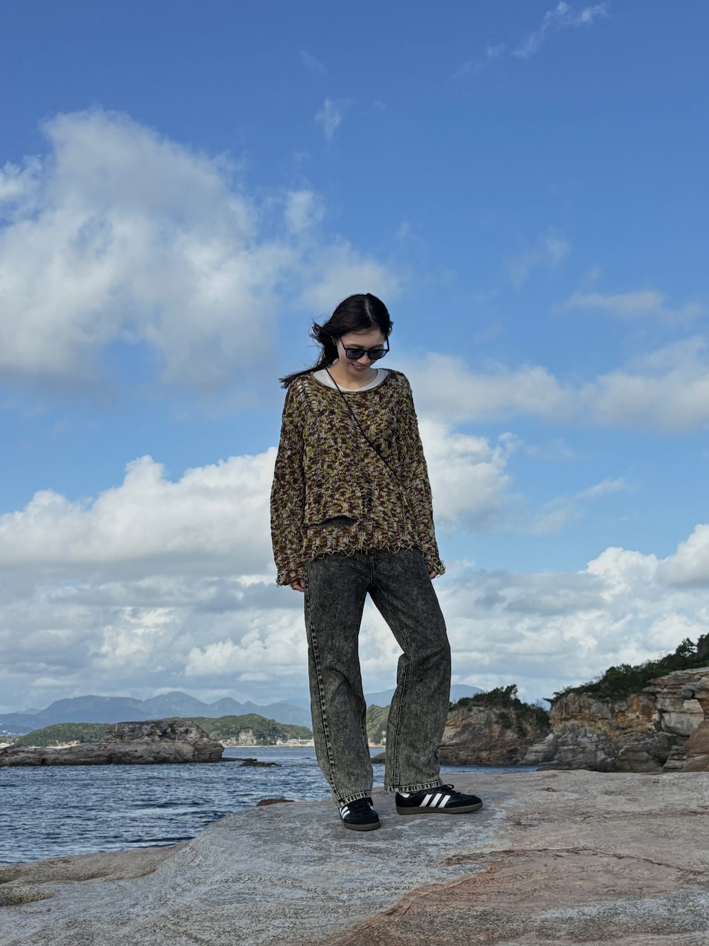 グリーン系のニット/セーター、グリーン系のデニムパンツ、ブラック系のスニーカーを着用したレディースの秋コーディネートの1枚目の写真