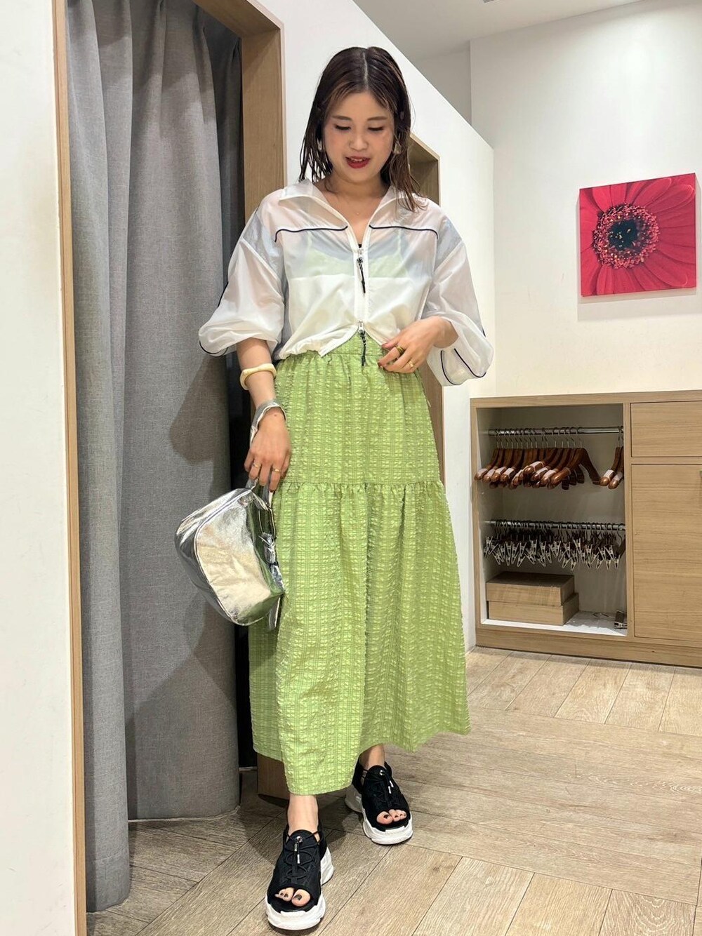 ブラック系のサンダル、グリーン系のワンピース、ホワイト系のブルゾンを着用したレディースの春コーディネートの1枚目の写真