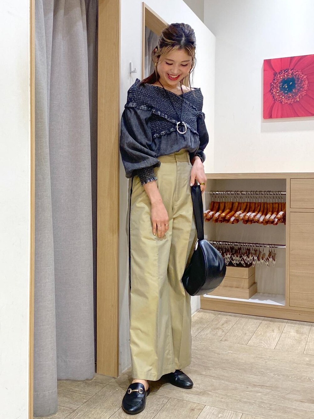 ベージュ系のスラックス、ブラック系のシャツ/ブラウス、ブラック系のハンドバッグを着用したレディースの春コーディネートの1枚目の写真