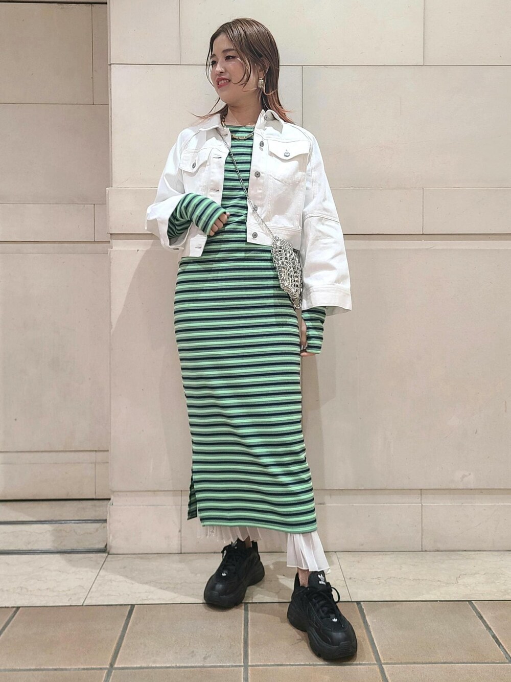 ホワイト系のデニムジャケット、シルバー系のショルダーバッグ、ホワイト系のスカートを着用したレディースの冬コーディネートの1枚目の写真