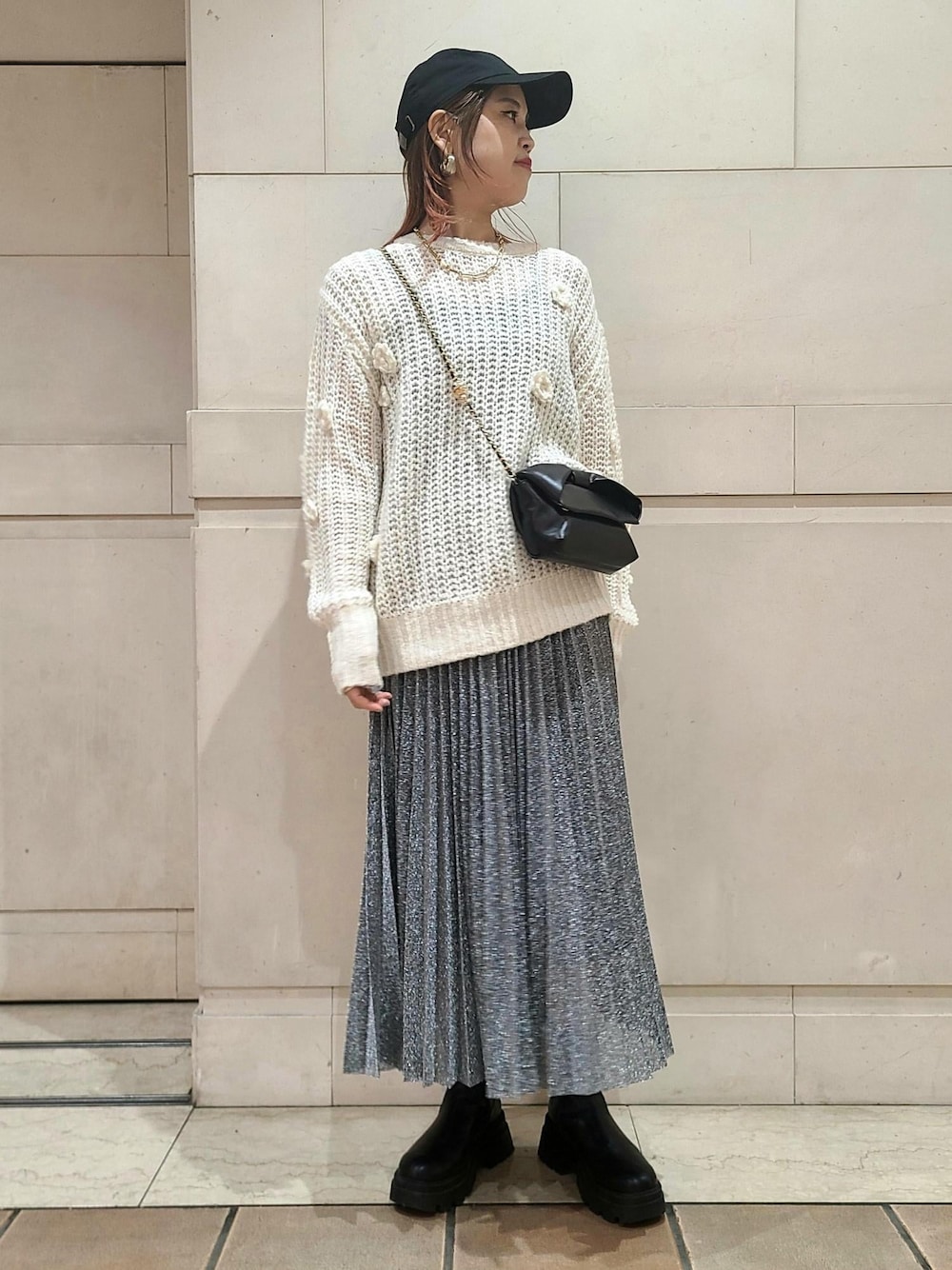 ブラック系のスカート、ホワイト系のニット/セーター、ブラック系のショルダーバッグを着用したレディースの冬コーディネートの1枚目の写真