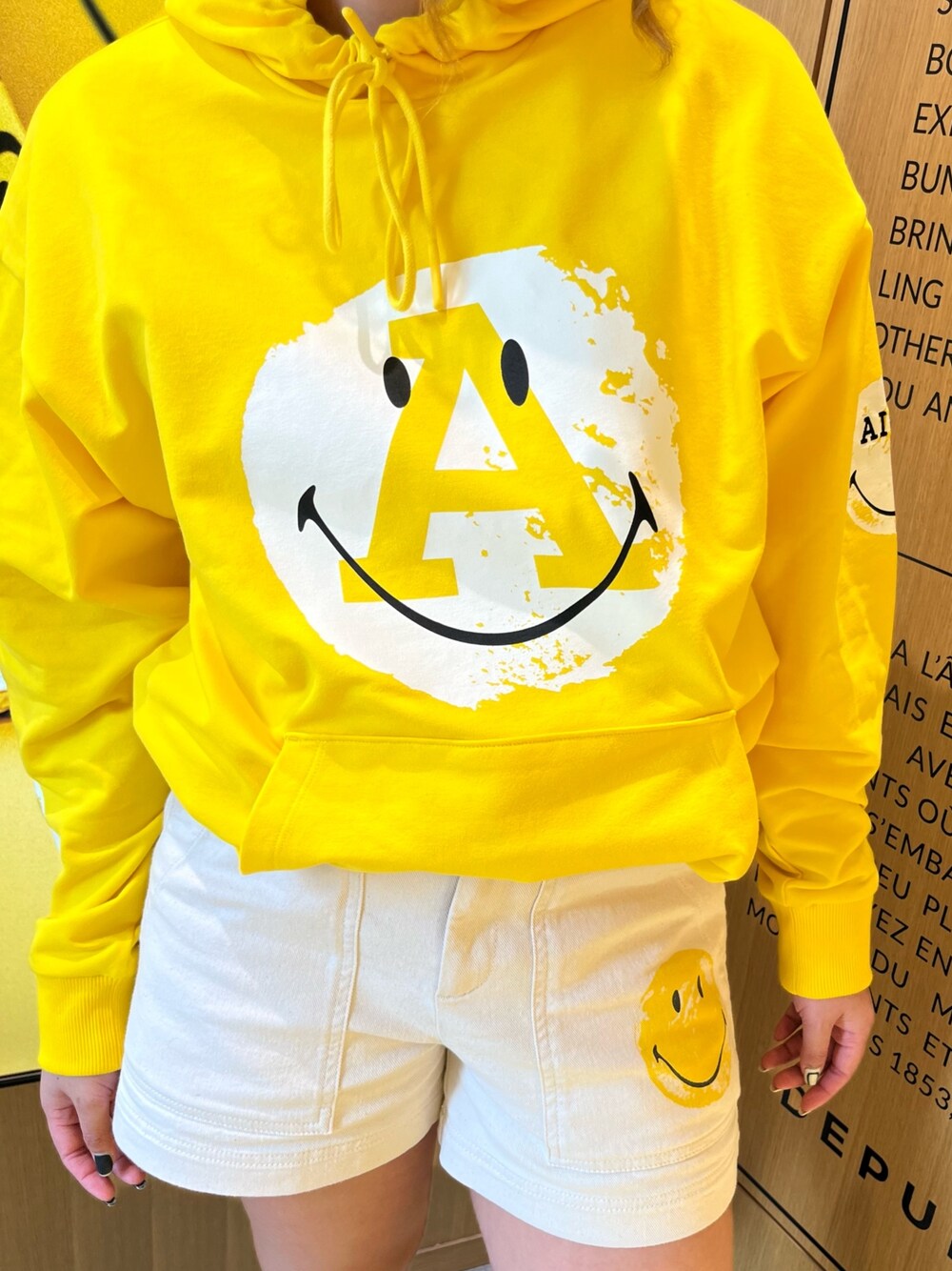 イエロー系のパーカー、グレー系のレインシューズ、ホワイト系のその他パンツを着用したレディースの春コーディネートの3枚目の写真