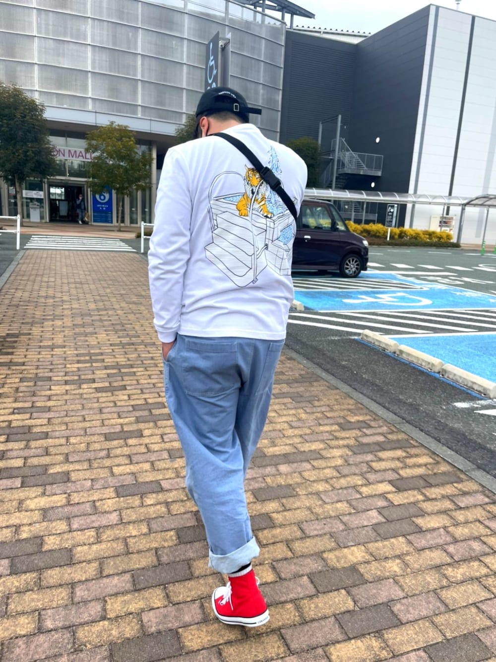 ホワイト系のTシャツ/カットソー、ブルー系のデニムパンツ、レッド系のスニーカーを着用したメンズの冬コーディネートの1枚目の写真