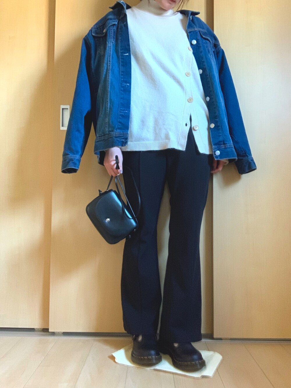 ブラック系のスラックス、ブラック系のローファー、ベージュ系のニット/セーターを着用したレディースの春コーディネートの1枚目の写真