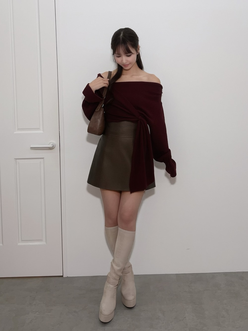 レッド系のTシャツ/カットソー、ブラウン系のスカート、ブラック系のブーツを着用したレディースの冬コーディネートの1枚目の写真