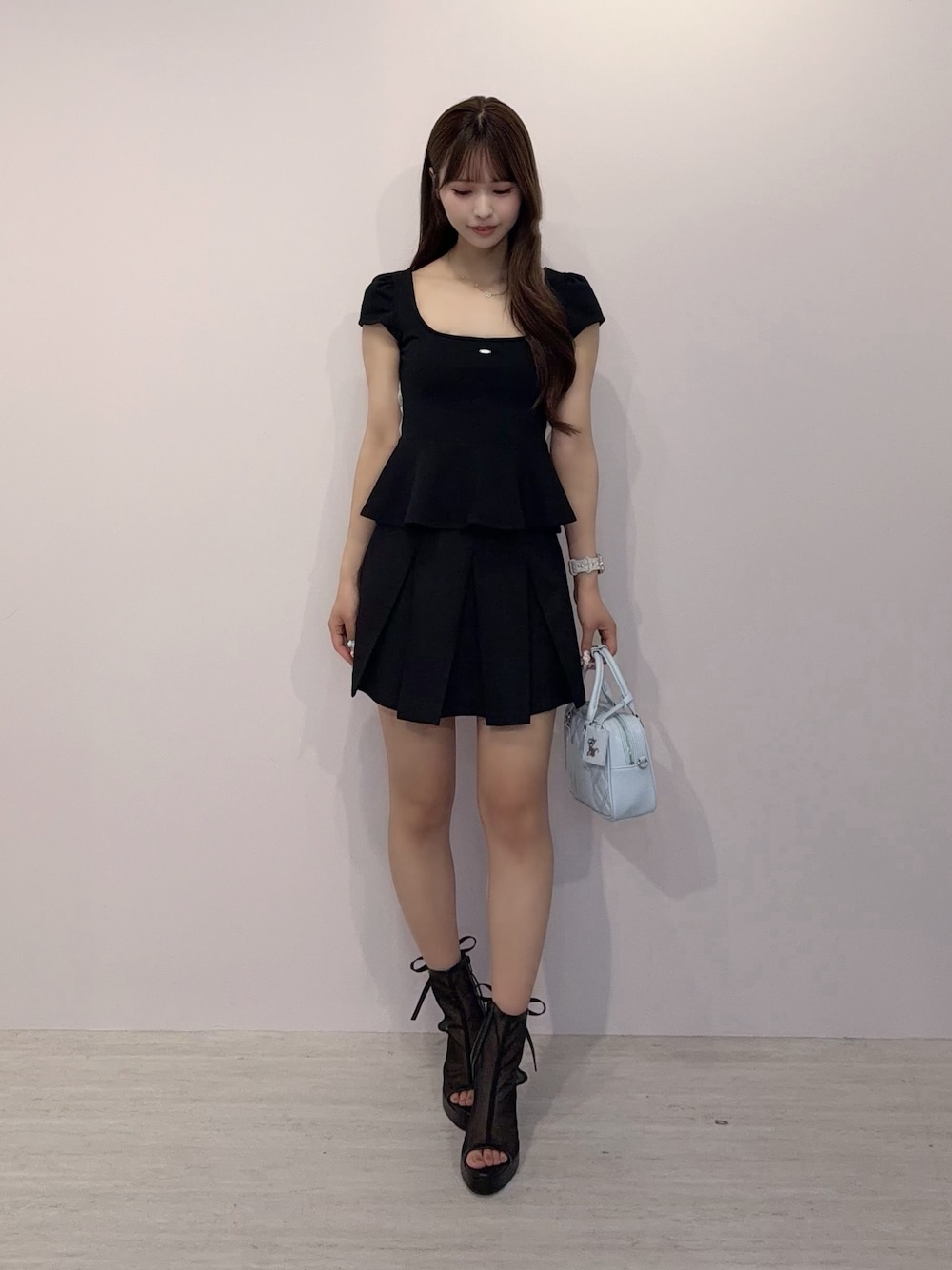 ブラック系のTシャツ/カットソー、ブラック系のスカート、ブラック系のハンドバッグを着用したレディースの春コーディネートの1枚目の写真