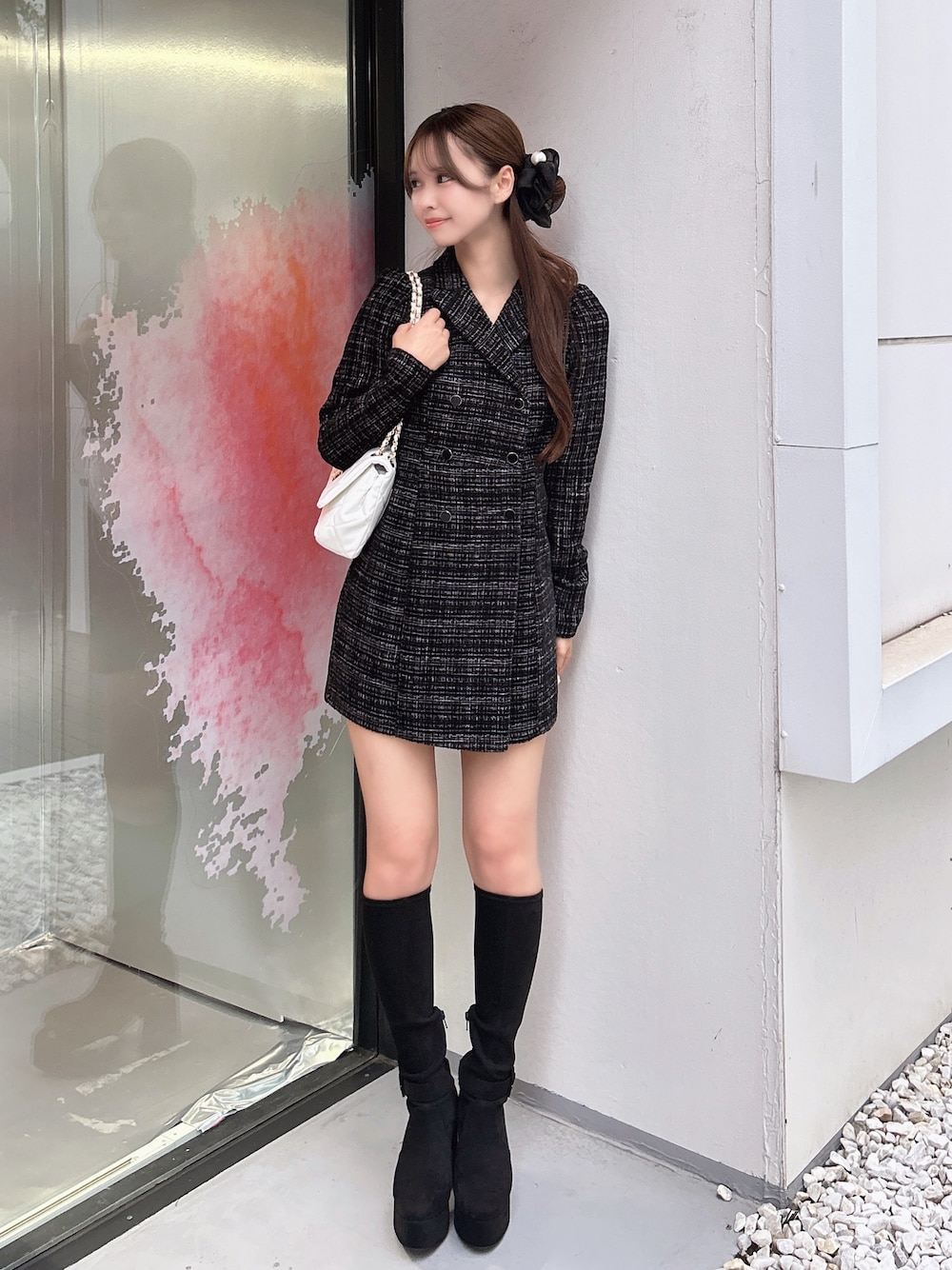 ブラック系のワンピース、ホワイト系のハンドバッグ、ブラック系のブーツを着用したレディースの秋コーディネートの1枚目の写真