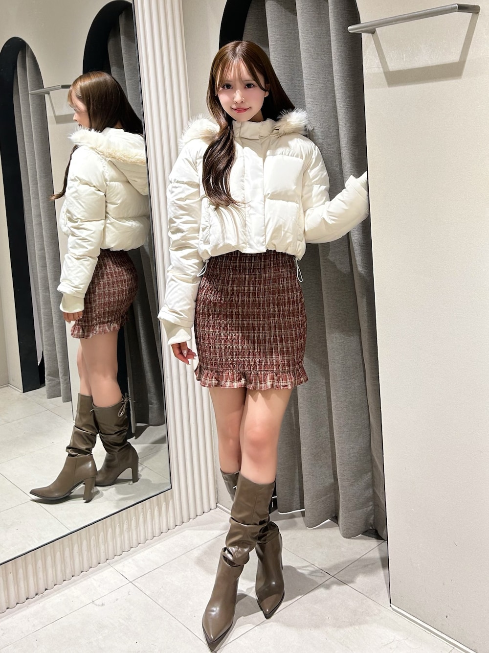 レッド系のワンピース、ホワイト系のブルゾン、ブラウン系のブーツを着用したレディースの秋コーディネートの1枚目の写真