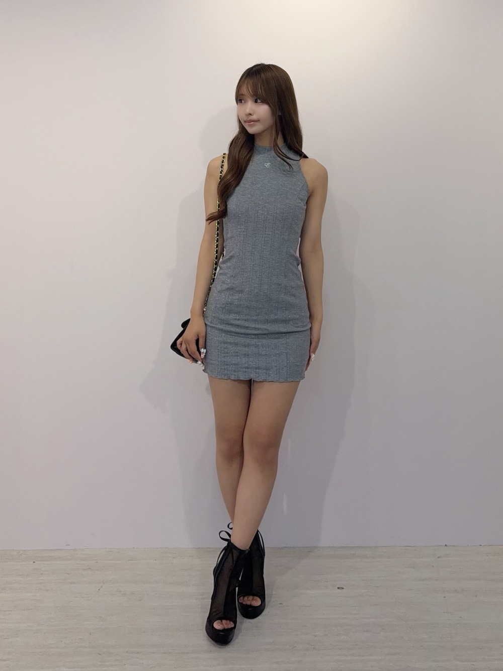 グレー系のワンピース、ブラック系のサンダル、ブラック系のハンドバッグを着用したレディースの夏コーディネートの1枚目の写真