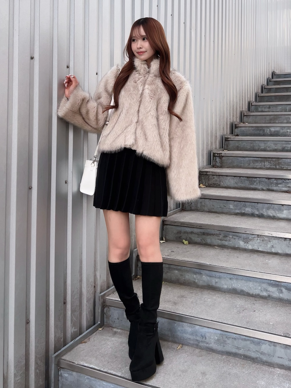 ベージュ系のブルゾン、ブラック系のワンピース、ブラック系のブーツを着用したレディースの冬コーディネートの1枚目の写真