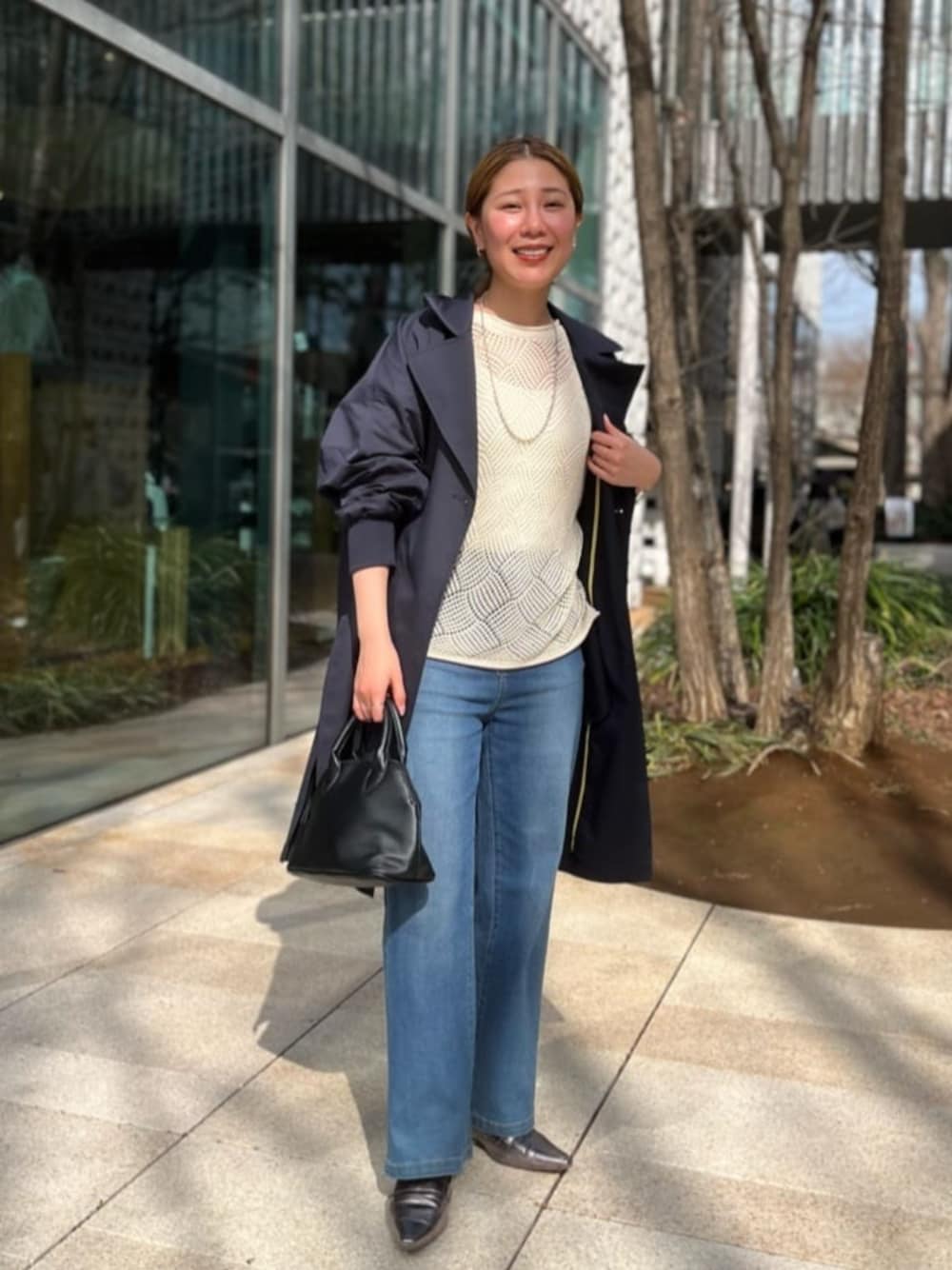 ホワイト系のニット/セーター、ブルー系のデニムパンツ、ブルー系のトレンチコートを着用したレディースの春コーディネートの1枚目の写真