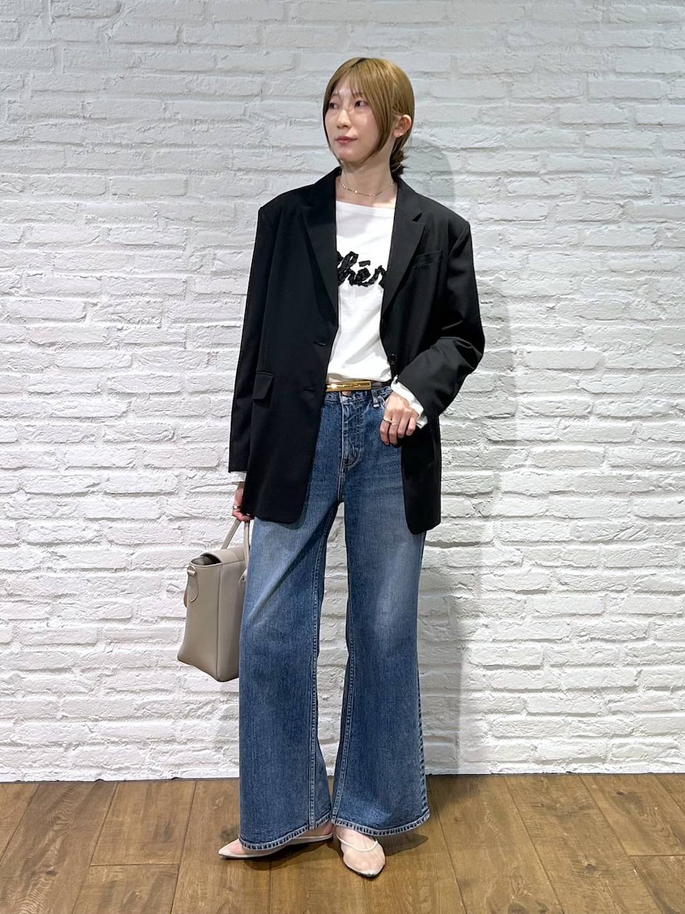 ベージュ系のパンプス、ブラック系のテーラードジャケット、ブルー系のデニムパンツを着用したレディースの冬コーディネートの1枚目の写真