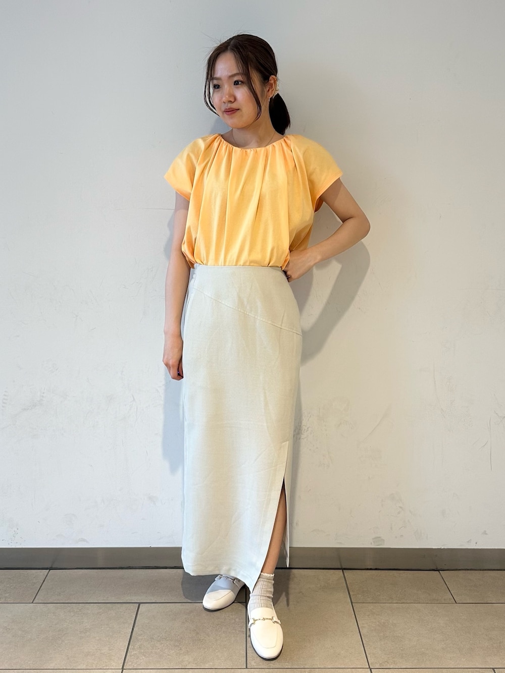 オレンジ系のTシャツ/カットソー、ベージュ系のスカート、ホワイト系のローファーを着用したレディースの夏コーディネートの1枚目の写真