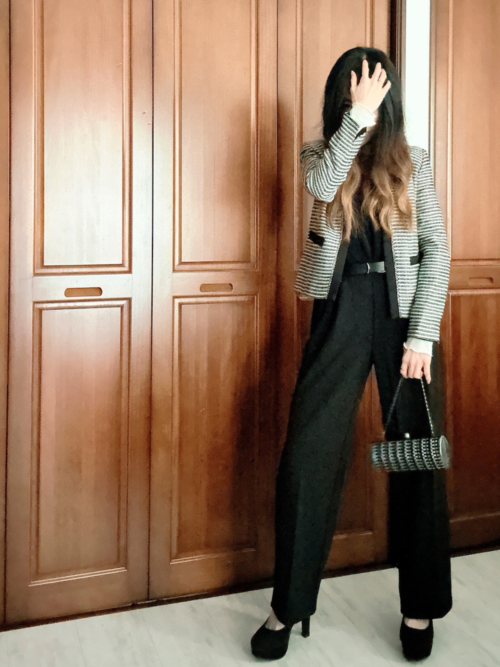 ブラック系のスーツセット、グレー系のクラッチバッグ、ブラック系のベルトを着用したレディースの春コーディネートの1枚目の写真