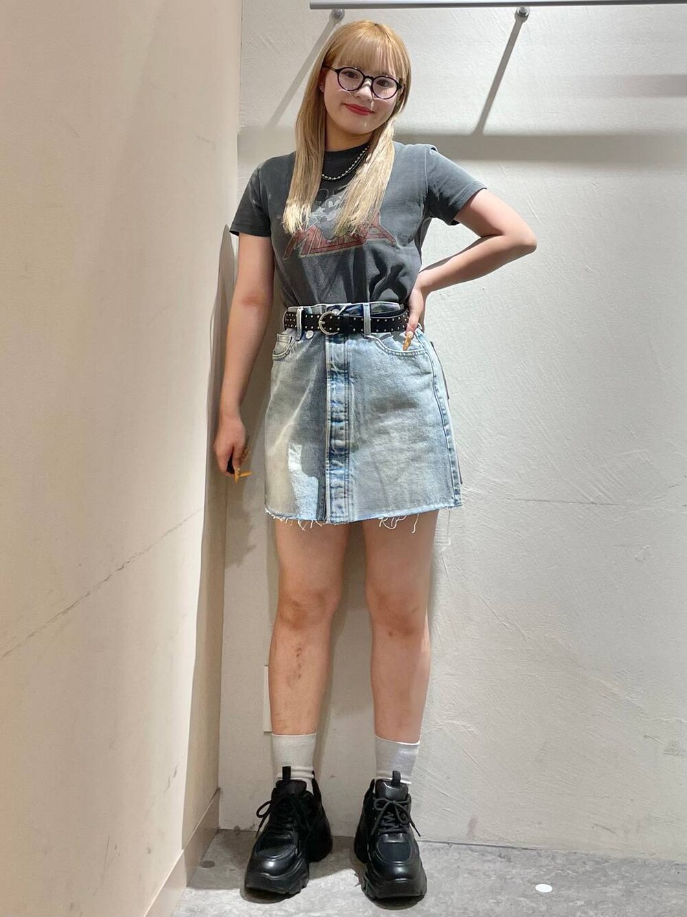 ブラック系のスニーカー、ブルー系のデニムスカート、グレー系のTシャツ/カットソーを着用したレディースの夏コーディネートの1枚目の写真